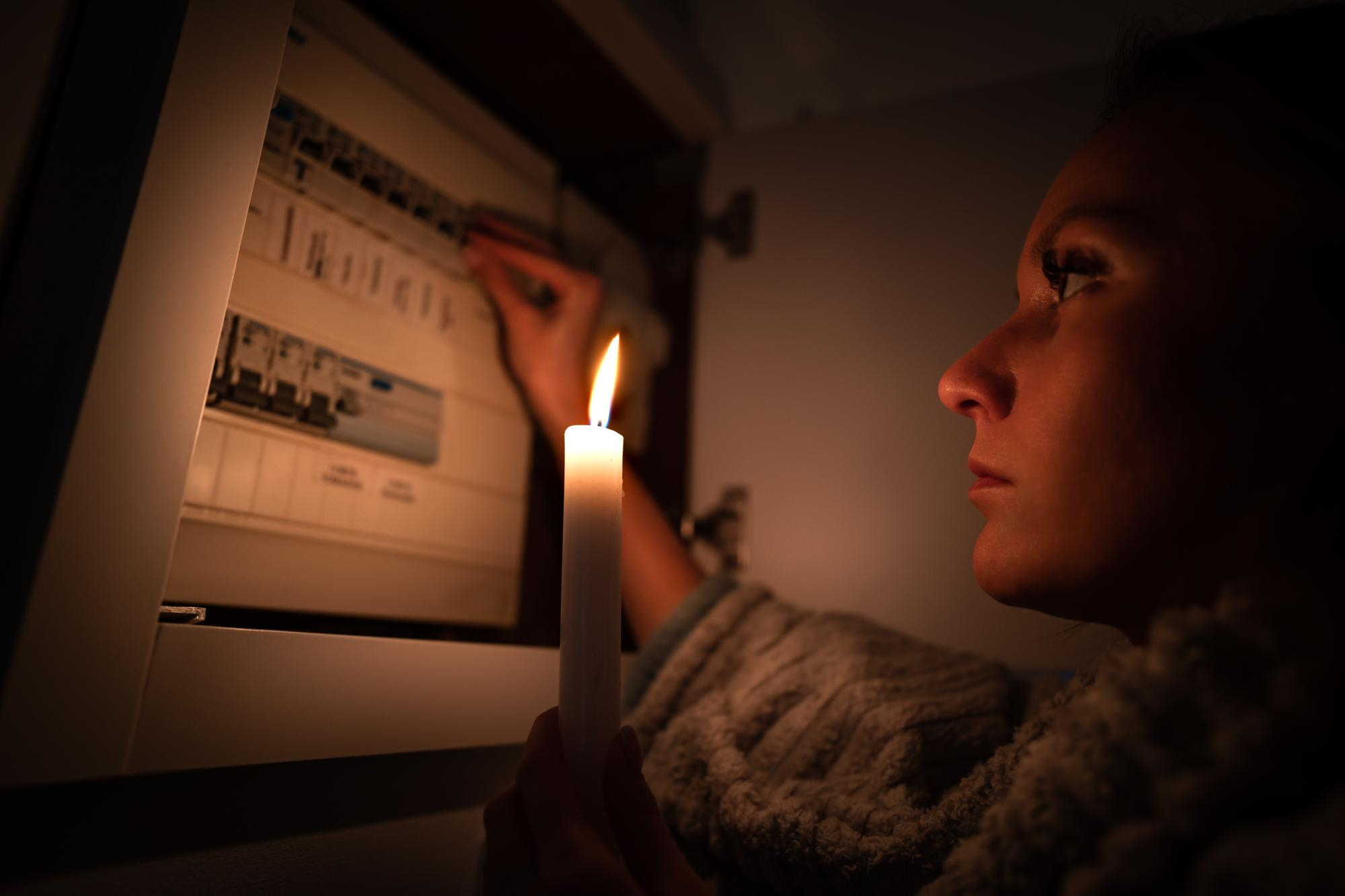 Mulher com vela na mão em corte de energia