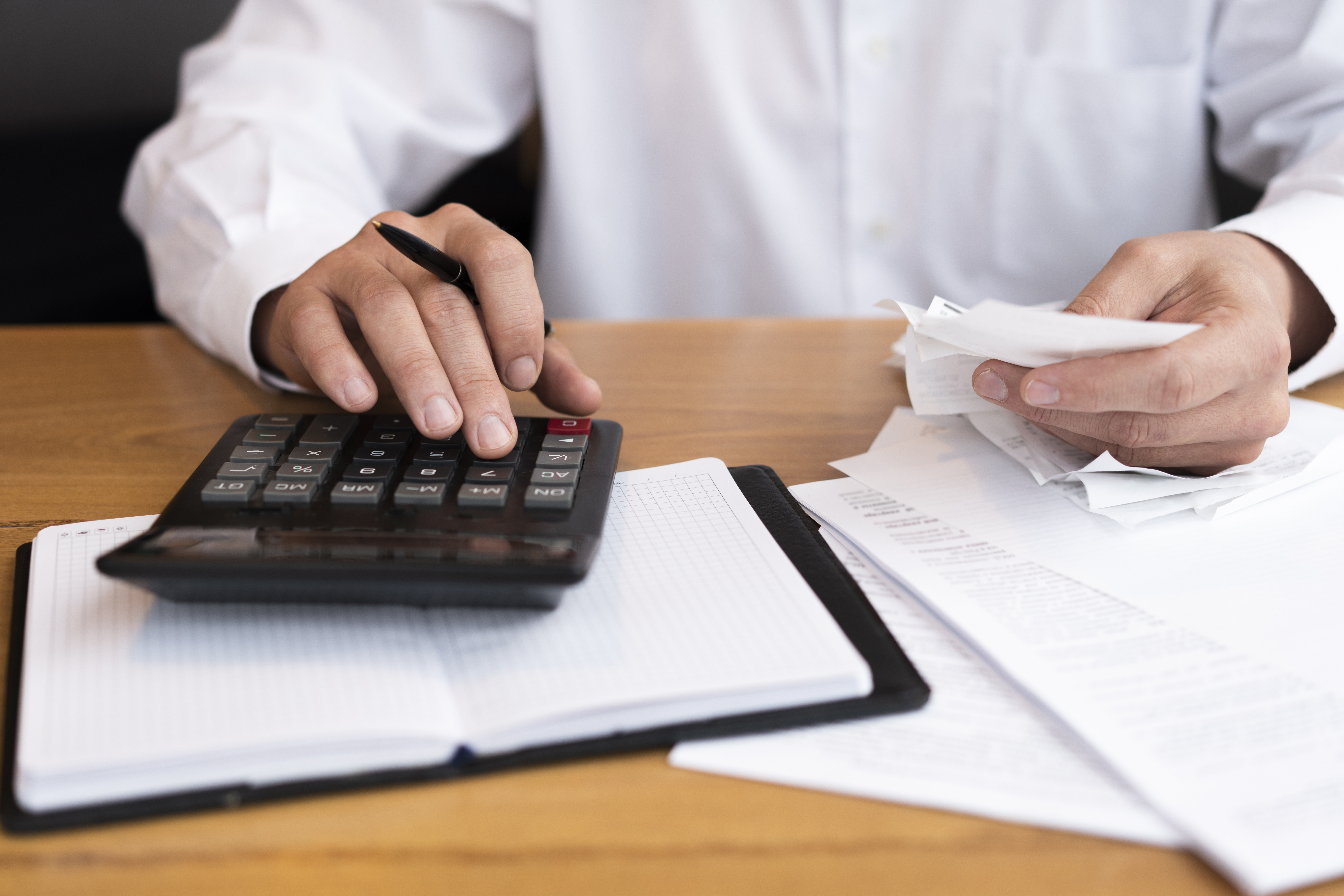 homem faz contas na calculadora em sua mesa de trabalho