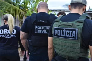 Três policiais civis do Amazonas (uma mulher e dois homens) de costas. Desembargadores invalidaram critérios de tempo de serviço público como desempate para promoção na Polícia Civil do Amazonas.